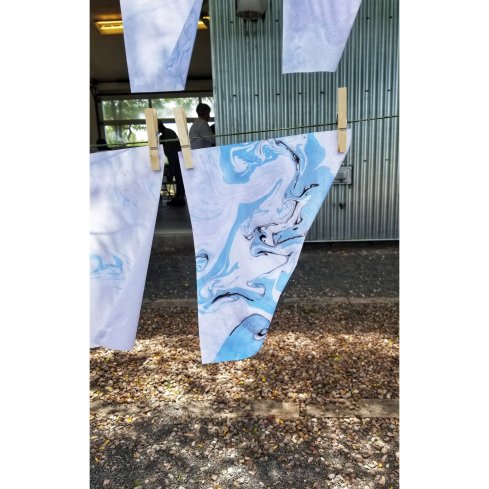 Blue, black, and white suminagashi drying on a clothesline, twisting in the wind