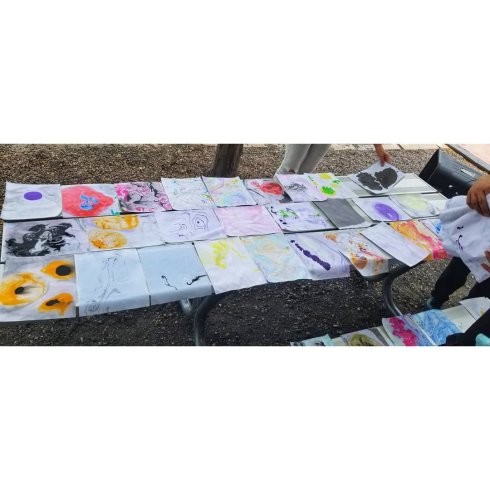 A park bench tabletop completely covered in drying marbled paper