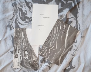 3 cards with black ink and renga text lying on top of silk suminagashi.